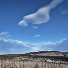 Panorama view of the snow-covered mountain Brocken with a few clouds on the sky.